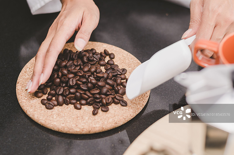 在咖啡店里，咖啡师手牵着手，用设备仔细测量咖啡豆的质量，制作美味的咖啡图片素材