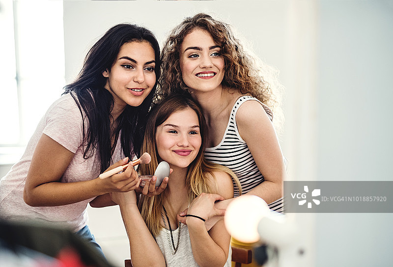 三个少女朋友在家里化妆，玩得很开心。图片素材
