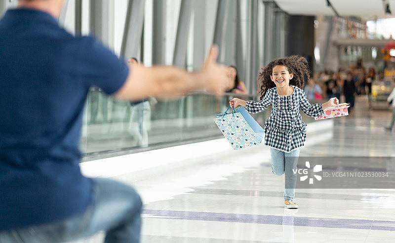 漂亮的小女孩在机场迎接她的爸爸，兴奋地向他跑去图片素材