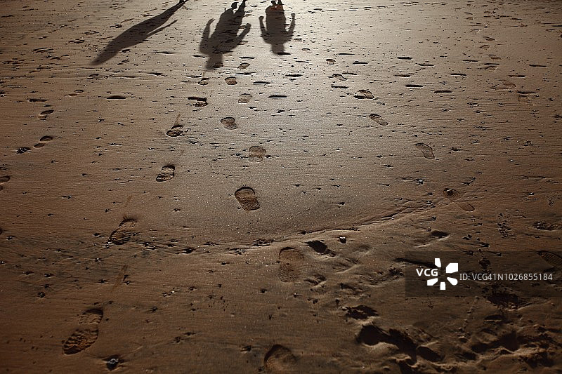 沙滩上行走的人的脚印和影子图片素材