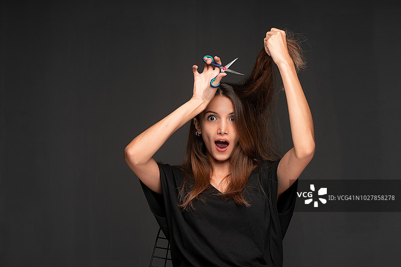 一个年轻女子在剪自己的头发图片素材