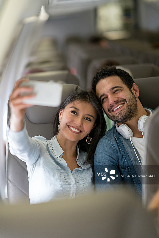快乐的拉丁美洲夫妇在飞机上自拍图片素材