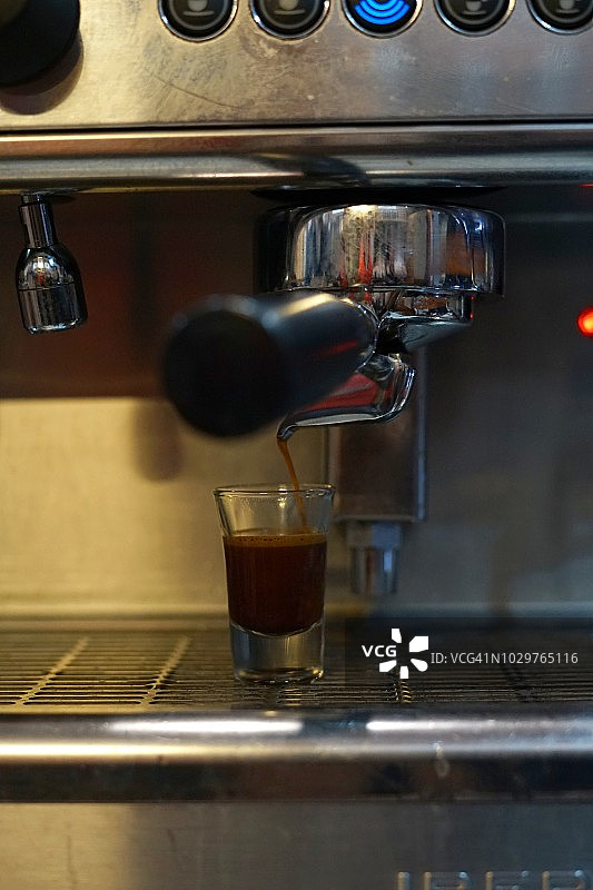当地咖啡店的浓缩咖啡机将新鲜的咖啡倒入杯子图片素材