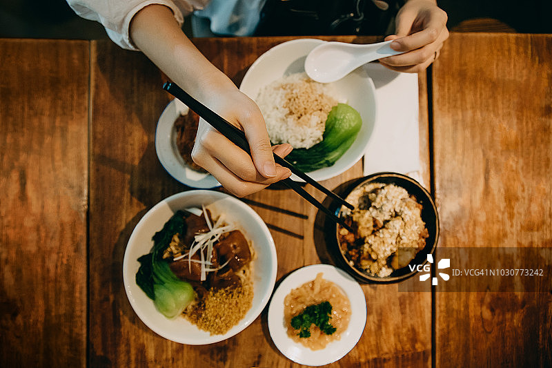 头顶上的女人享受新鲜烹制的饭菜在当地的亚洲餐厅图片素材