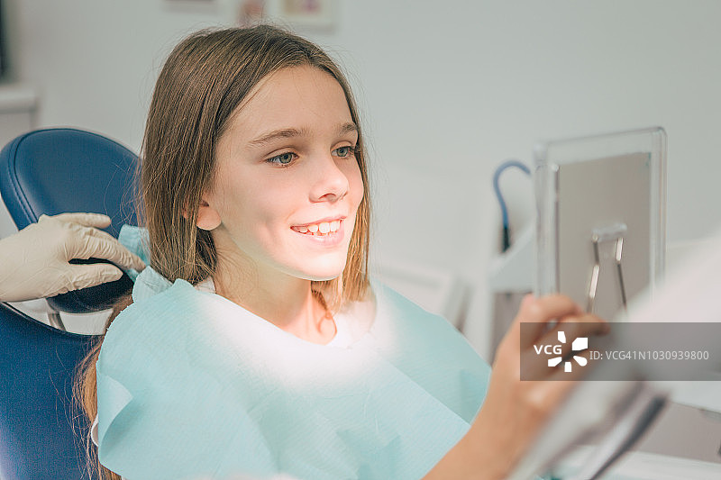 儿科牙医。一个年轻女孩在工作结束后看她的牙齿。图片素材
