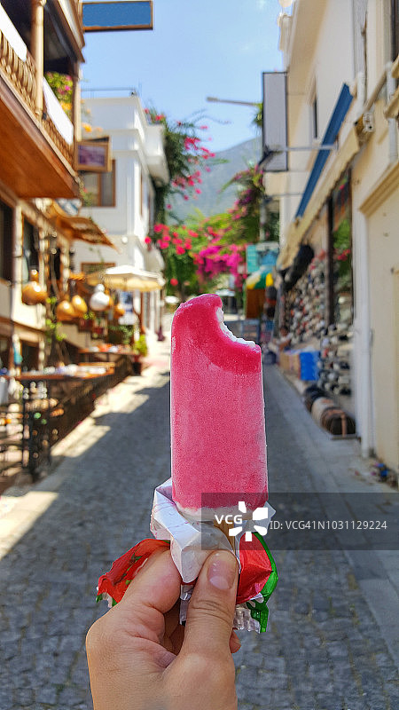 在街道背景下的手握粉红色冰淇淋的特写图片素材