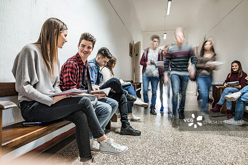 在学校走廊里，快乐的学生们一边学习一边聊天。图片素材