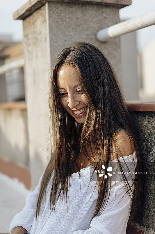 年轻女子在屋顶露台上放松的微笑肖像图片素材