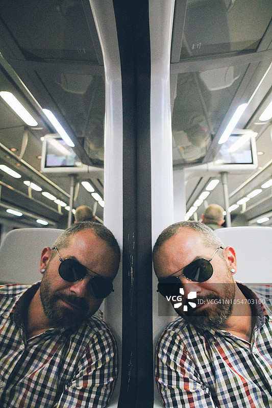 一名戴着太阳镜的中年男子倒映在火车车窗上图片素材