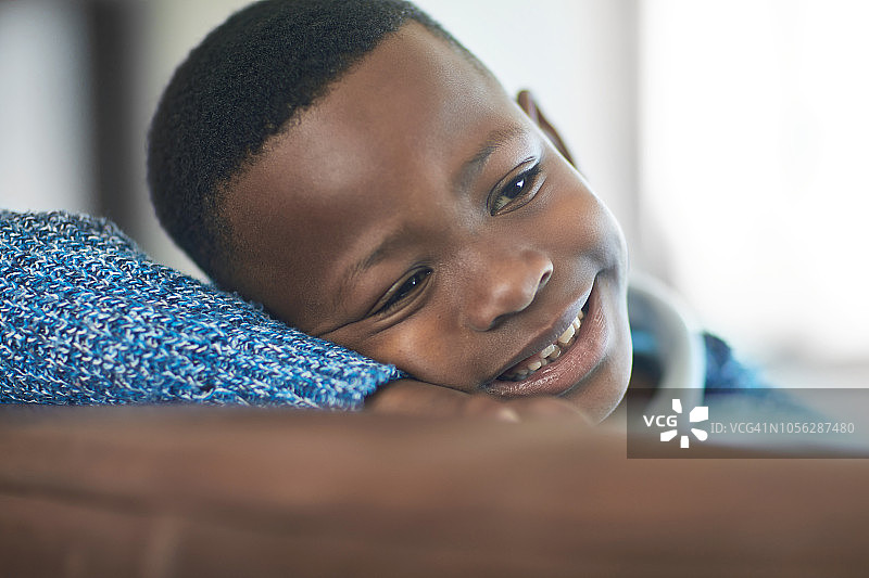 一个快乐的非洲小男孩在家里的沙发上放松的特写图片素材
