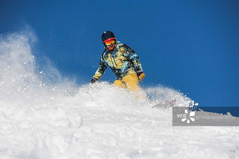穿着鲜艳运动服的滑雪者在一个粉状山坡上滑行图片素材