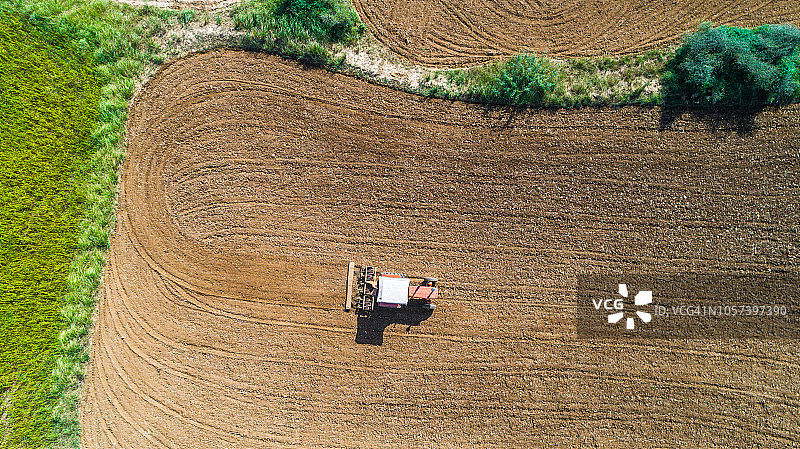 用拖拉机在红壤中犁地的鸟瞰图图片素材