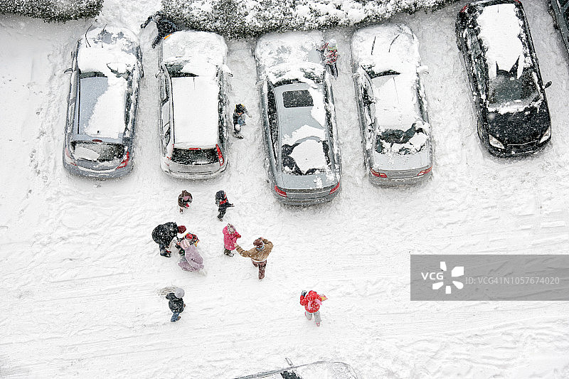 鸟瞰冬天一群孩子在白雪覆盖的城市街道上玩耍图片素材