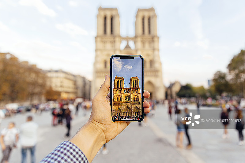 游客用智能手机拍摄巴黎圣母院，个人透视视图图片素材