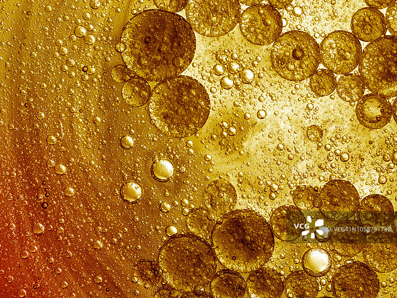 完整的抽象形状和纹理框架，形成的泡沫和水滴在金色的液体背景。图片素材
