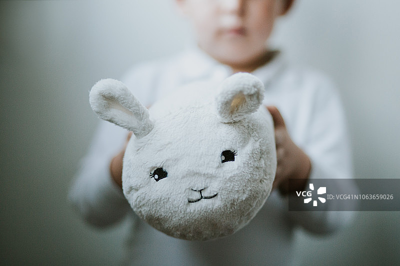 可爱的小男孩在室内玩毛绒玩具(白兔)图片素材
