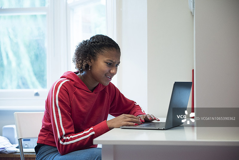 十几岁的女孩在书桌前玩电脑图片素材