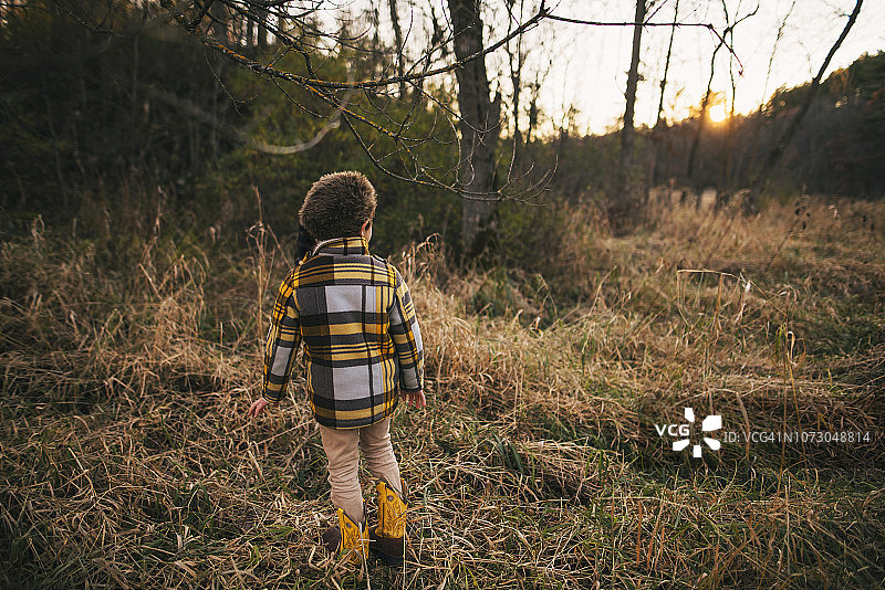 男孩站在秋天的树林里，美图片素材