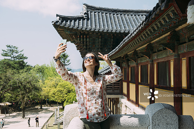韩国庆州，一名快乐的女子在八宫寺用手机自拍图片素材