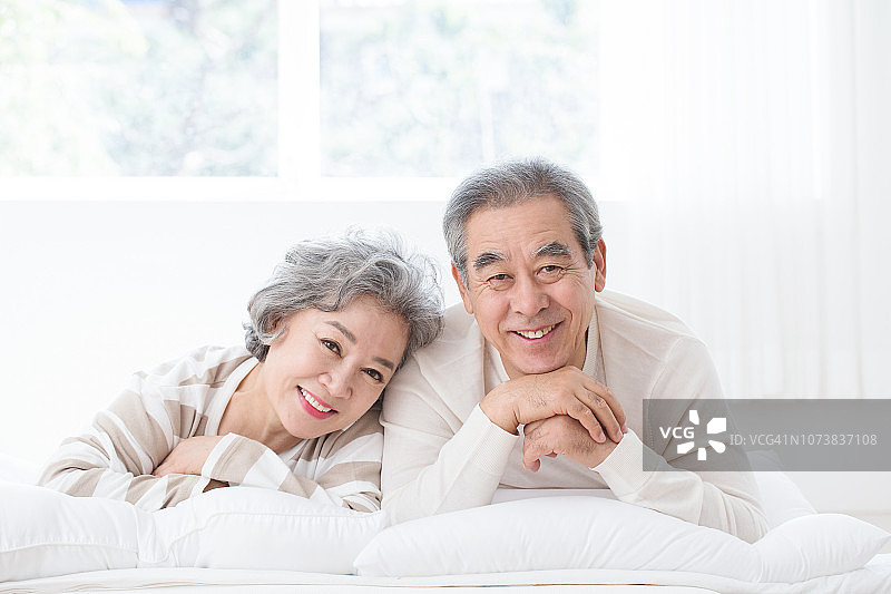 微笑的老夫妇躺在床上互相耳语图片素材