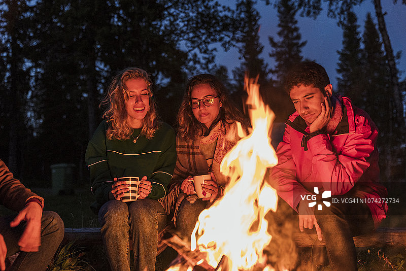 一群朋友围坐在篝火旁聊天喝茶图片素材