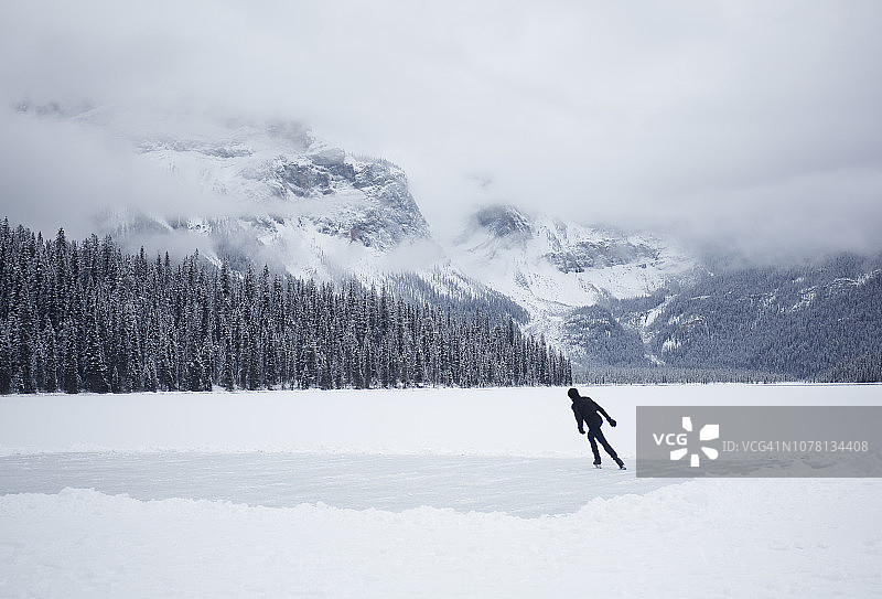 年轻人在结冰的湖面上滑冰。图片素材