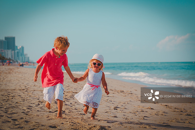 快乐的小男孩和女孩在海滩上奔跑玩耍图片素材