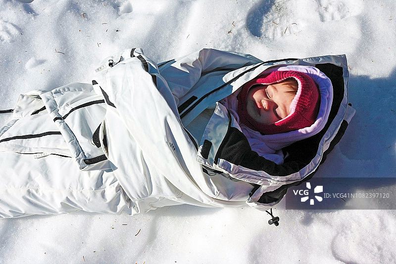 罗马尼亚特兰西瓦尼亚的Alpina Blazna公园里，为了铁的健康，孩子穿着父母的大衣在外面的雪地里睡觉图片素材