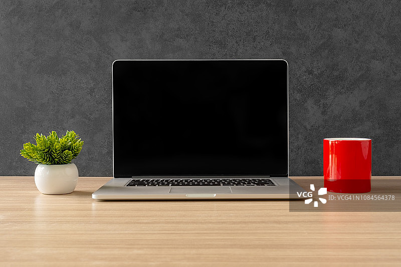 笔记本电脑和红色咖啡杯放在办公桌上图片素材