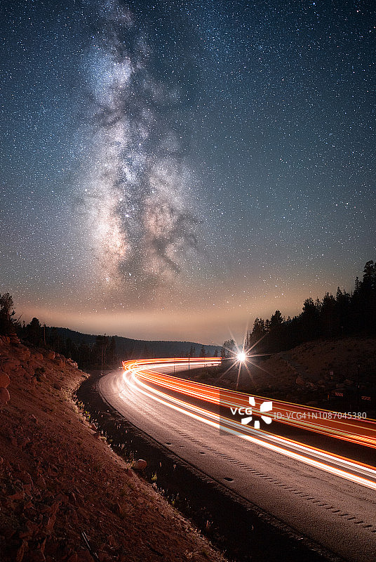 在美国内华达玫瑰山的山路上行驶的汽车上方的银河图片素材