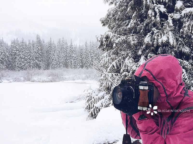 一位女摄影师在大雪中徒步旅行时准备好了她的相机图片素材