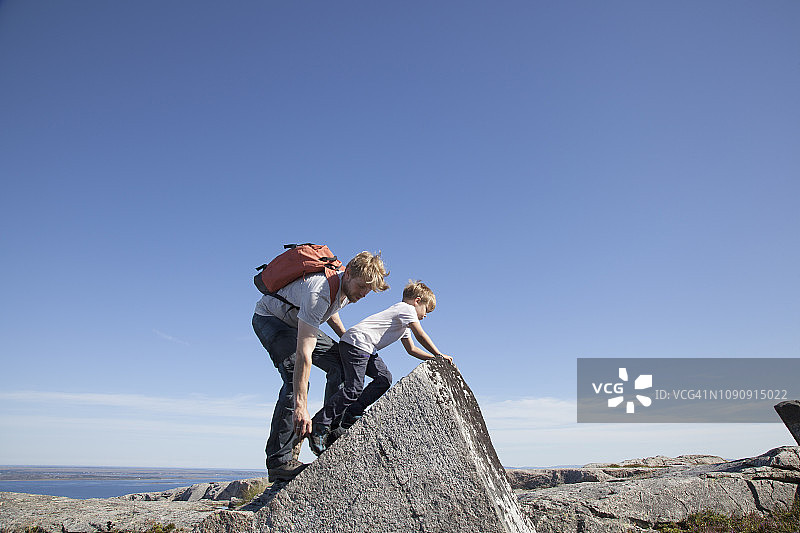 男孩和父亲在挪威莫尔奥格罗姆斯达尔的入口攀爬岩石图片素材