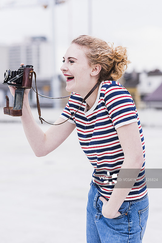 一个笑着的年轻女人带着老式相机的肖像图片素材