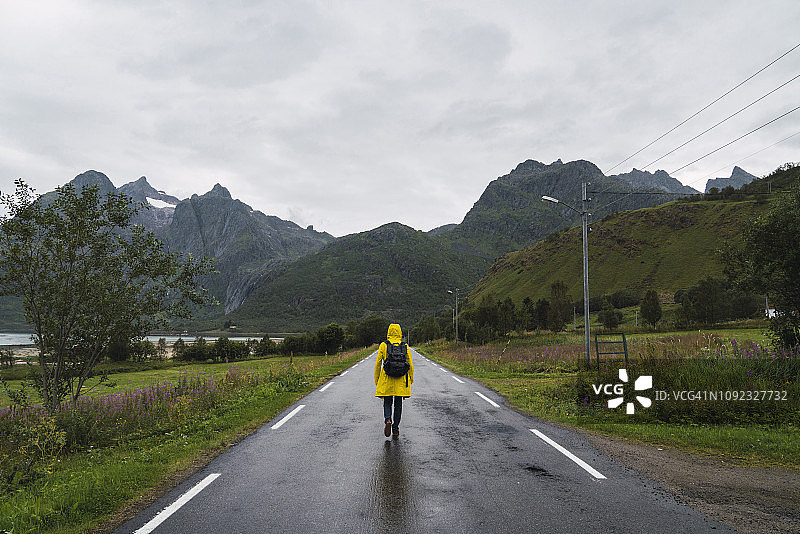 挪威，拉普兰，韦斯特伦群岛，年轻人走在空旷的路上，后视眼图片素材