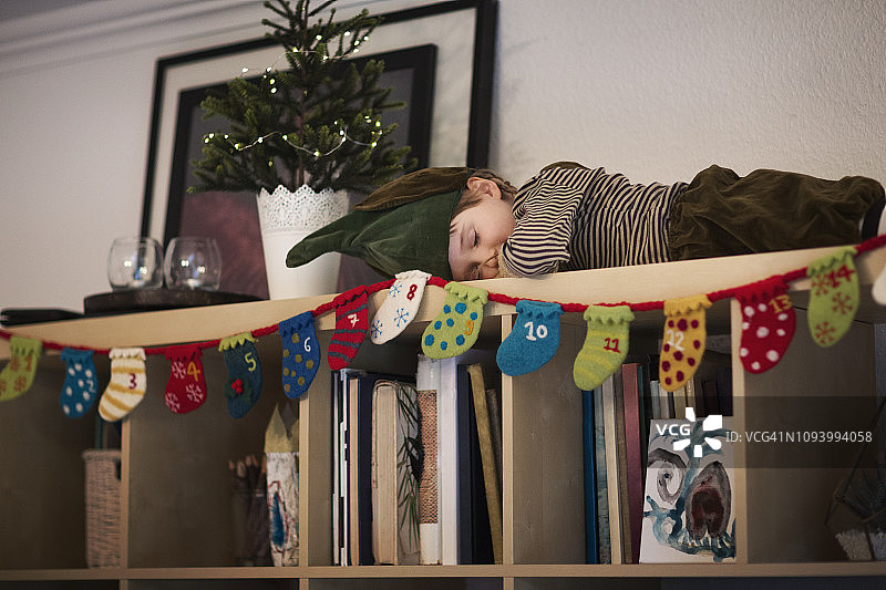 孩子(6-7岁)打扮成精灵，睡在书架上图片素材