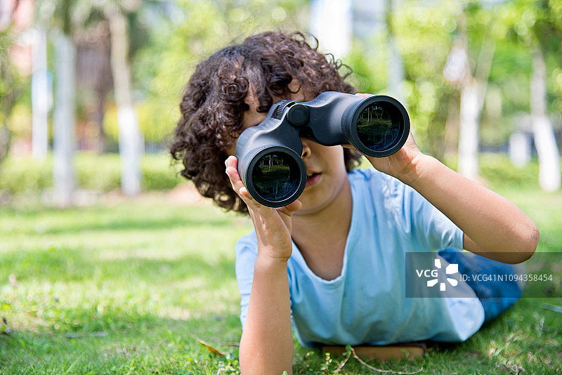 小男孩拿着望远镜在公园里图片素材