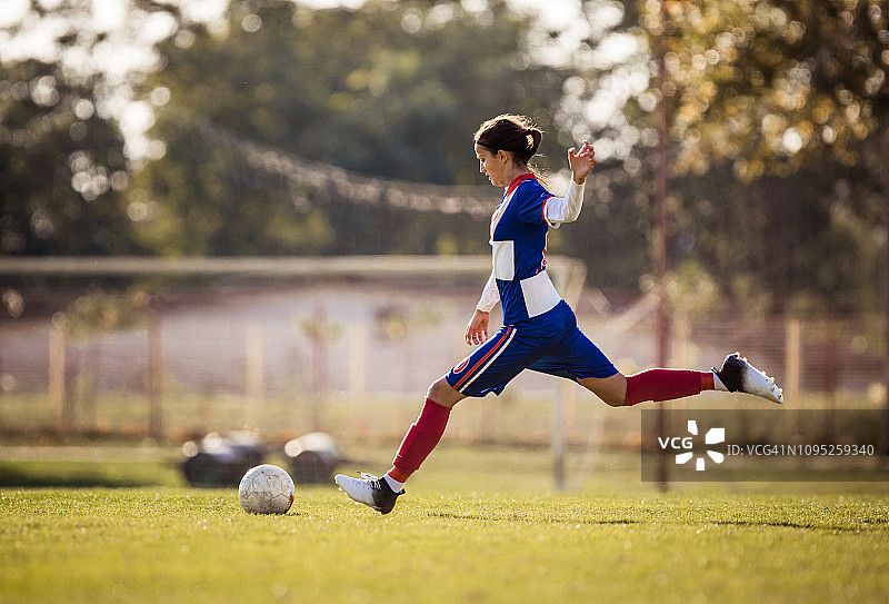 一名十几岁的足球运动员在比赛中正要踢球。图片素材