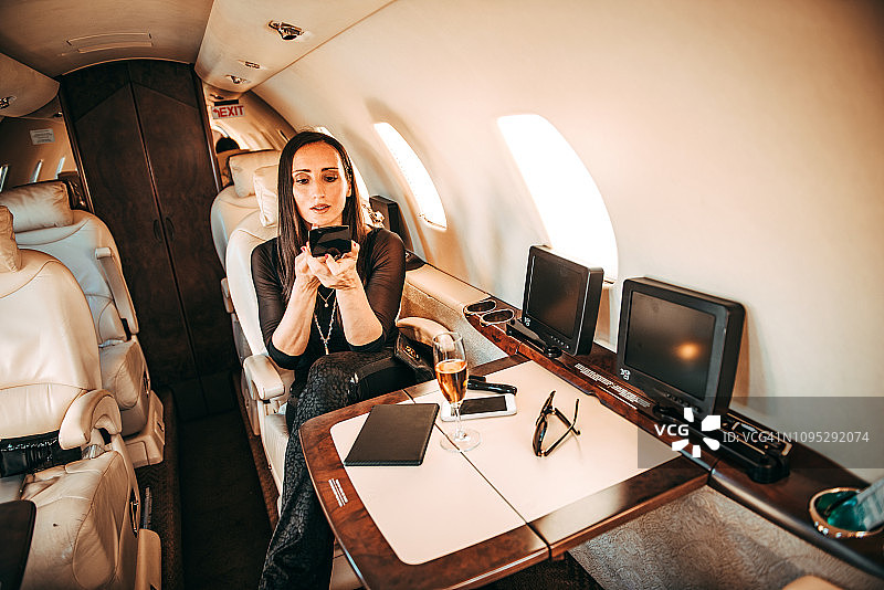 成功女性在乘坐私人飞机时用小镜子补妆图片素材