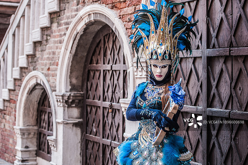 穿着迷人的金色和蓝色服装的弦乐器女子在威尼斯狂欢节图片素材