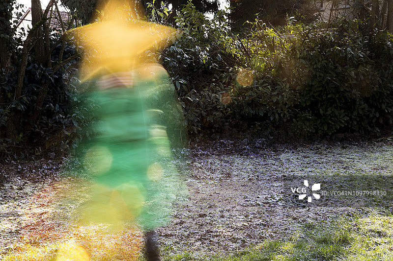 一个穿着绿色衣服拿着黄色星星的小孩的模糊动作图片素材