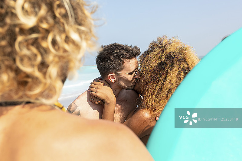一对情侣和朋友在海滩上互相亲吻图片素材