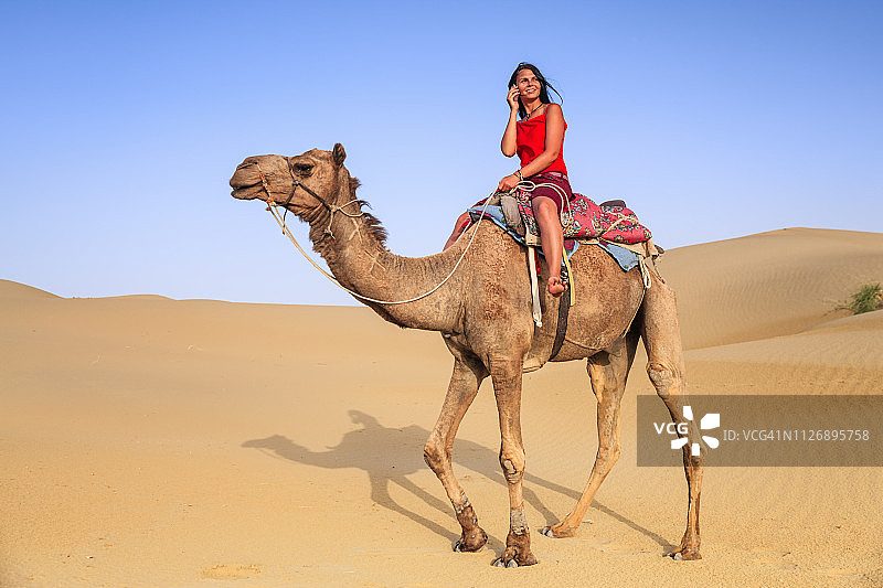 骑在骆驼上的年轻女性游客图片素材