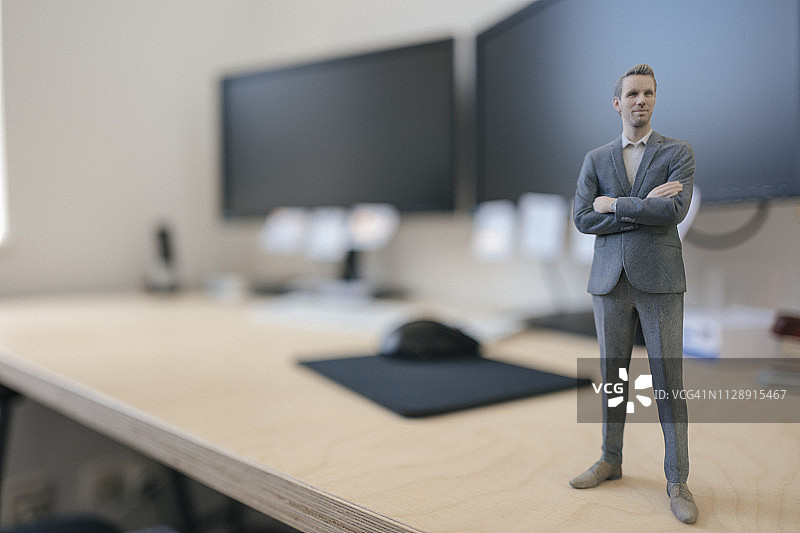 现代办公室里站在办公桌上的商人雕像图片素材