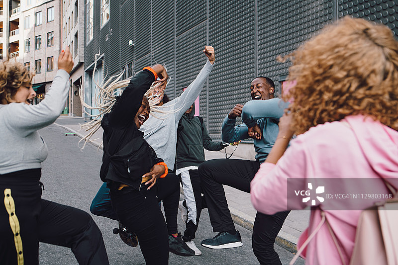 快乐的朋友们在街上跳舞，前面站着一个女人图片素材