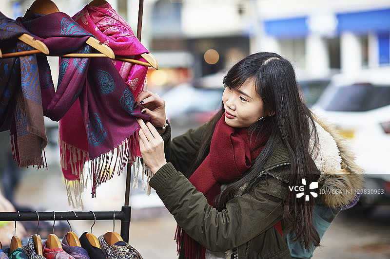 一名年轻女子在市场摊位上买围巾图片素材