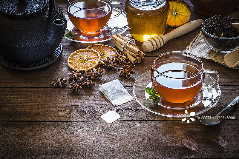 喝茶时间:一杯茶，肉桂棒，八角，橘子干放在木桌上图片素材