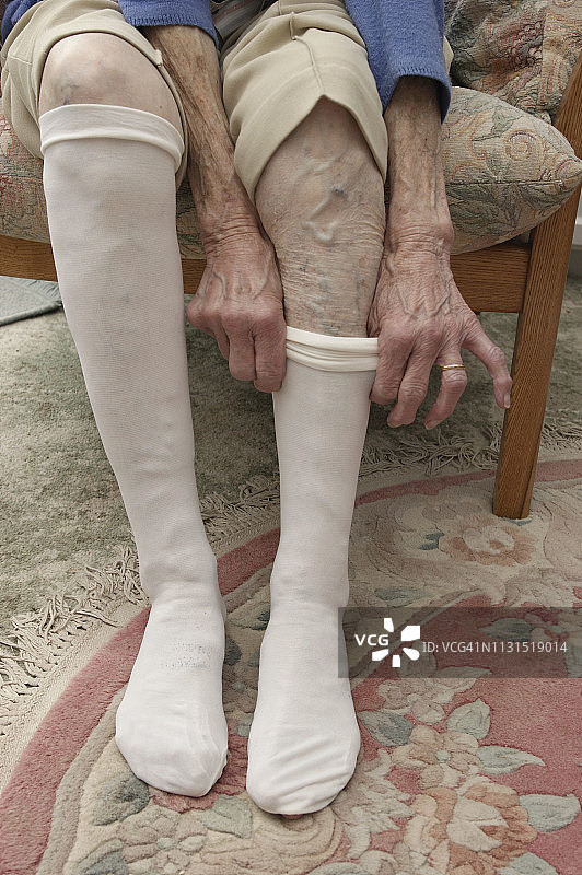 老奶奶正在穿压缩支撑袜图片素材
