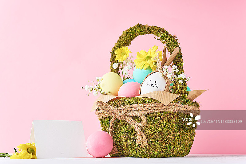 复活节的概念。复活节彩蛋装饰篮子与鲜花在粉红色的背景图片素材