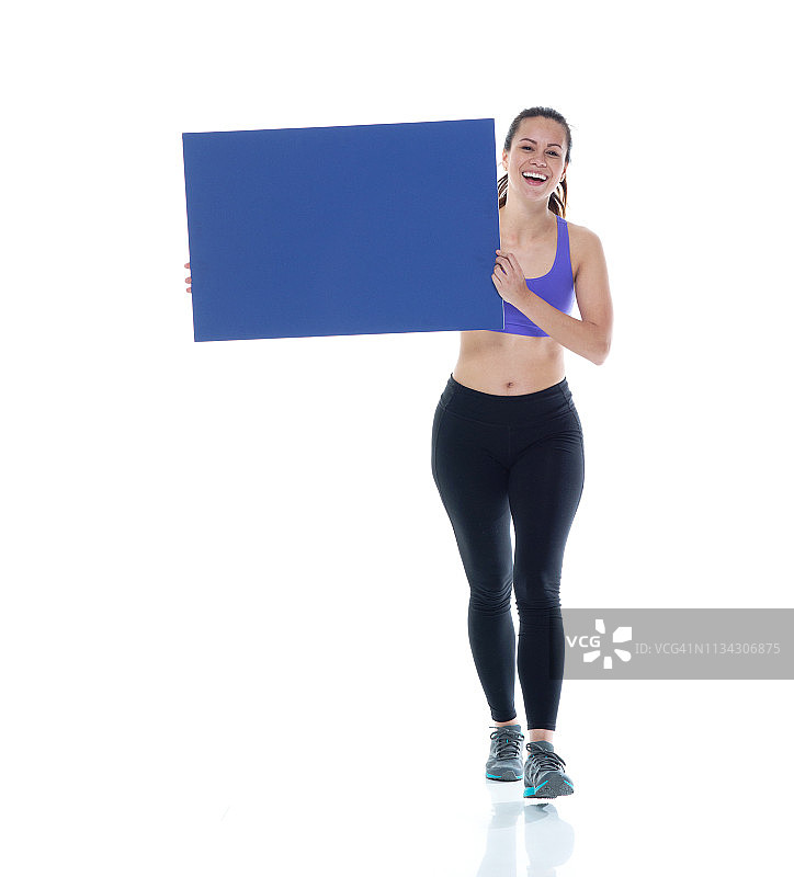 穿着运动服的漂亮女人正举着蓝色的标语牌走着图片素材
