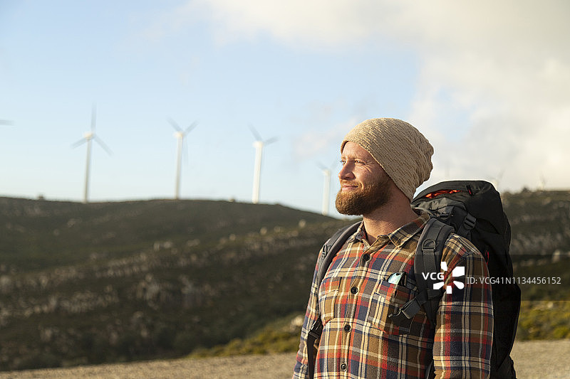 西班牙，安达卢西亚，塔里法，微笑的男子在徒步旅行与风力涡轮机的背景图片素材
